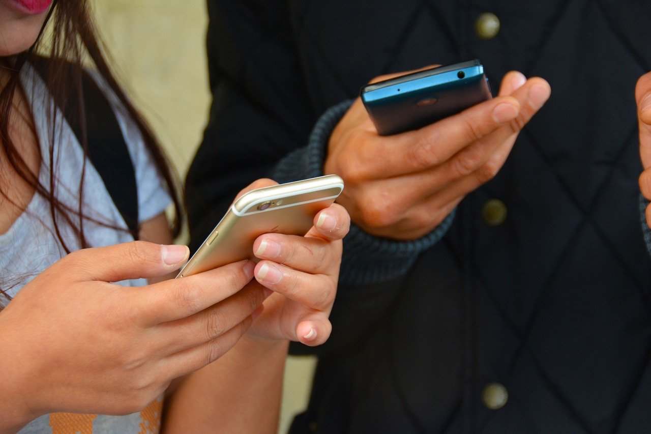 Photo de deux personnes en train d'utiliser leur téléphone
